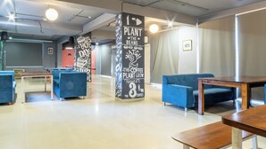 A modern indoor space with blue sofas, wooden tables, and a central pillar with motivational text. - Housr Sector 69 Gurgaon Near Sohna Road (Gurugram)