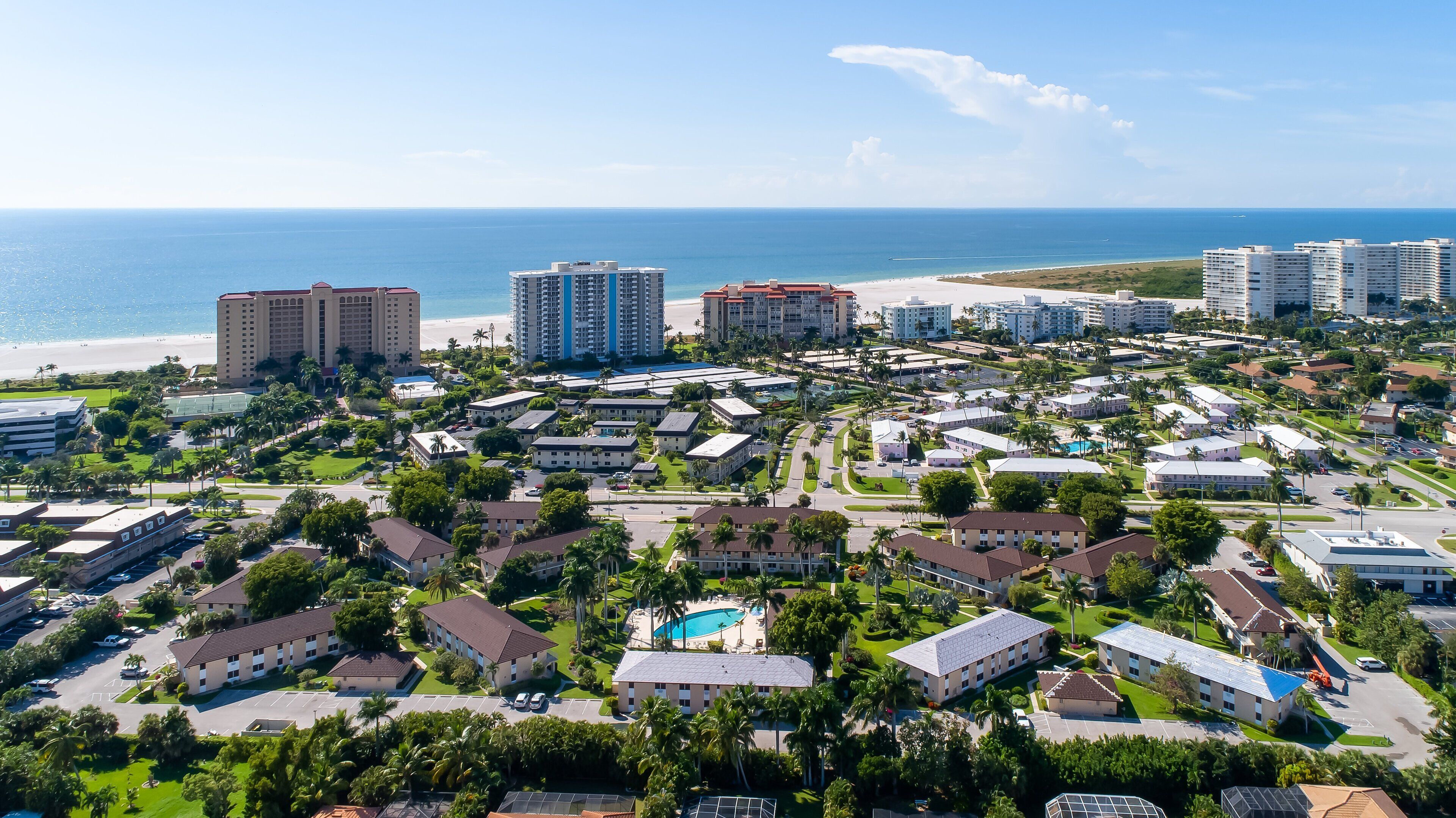 A coastal resort area with multiple hotel buildings, a beach, and a clear view of the ocean.