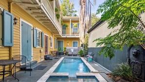 A pool area with a wooden deck, outdoor furniture, and a small pool.
