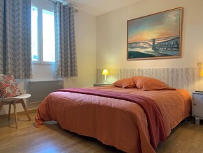 A bedroom with a large bed, two bedside lamps, a radiator, a chair, and a painting of a bridge. - "Villa l'Amboise" charm and comfort**** in Baie de Somme for 10 people (PENDÉ)
