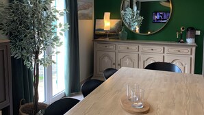 A dining area with a wooden table, chairs, a large mirror, and a green wall. - "Villa l'Amboise" charm and comfort**** in Baie de Somme for 10 people (PENDÉ)
