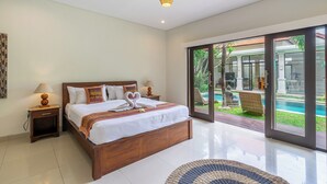 Un dormitorio moderno con una cama grande, dos mesitas de noche, una lámpara de techo y vistas a una piscina y zona de estar al aire libre.
