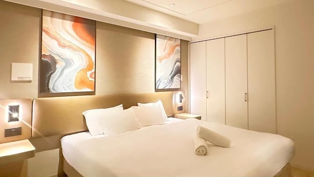 A hotel room with a large bed, a nightstand, and a wardrobe. - JStar Hotel Shinsaibashi (Osaka)
