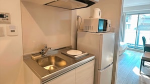 A compact kitchen with a stainless steel sink, a microwave, and a refrigerator. - JStar Hotel Shinsaibashi (Osaka)