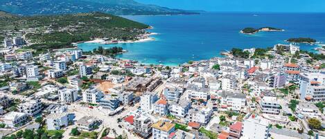 A coastal town with dense residential buildings, a marina, and a mountainous backdrop.