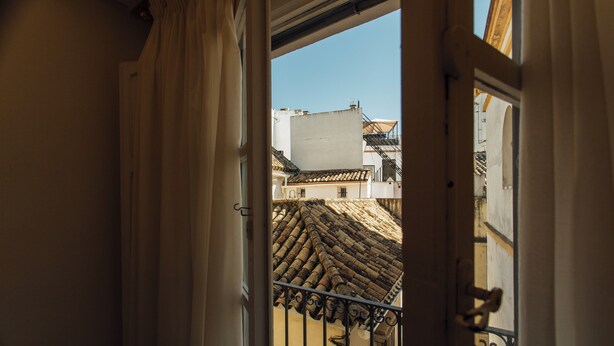 A view from a balcony with a tiled roof and wrought iron railing. - Boutique Abades Apartment II (Seville)