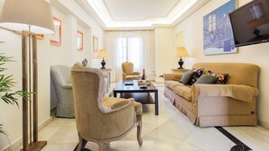 A living room with a beige sofa, a matching armchair, a coffee table, and a floor lamp. - Boutique Abades Apartment II (Seville)