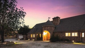 A stone house with a circular turret and a driveway leading to the entrance. - The Kingdom · 5000 SF Castle with Pool & Spa (Yucca Valley)