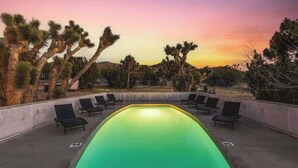 A swimming pool with lounge chairs, surrounded by desert vegetation. - The Kingdom · 5000 SF Castle with Pool & Spa (Yucca Valley)