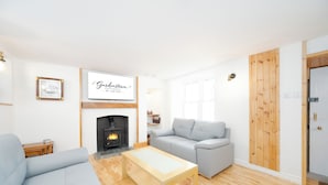 A modern living room with a fireplace, a grey sofa, a wooden coffee table, and a framed sign on the wall.