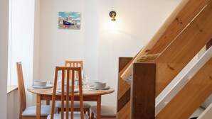 A dining area with a wooden table, chairs, and a painting of a boat on the wall.