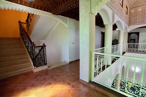 A staircase with ornate railings, a tiled floor, and a high ceiling with intricate patterns. - Les Terrasses Des Jardins  (Saâda)
