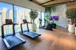 A gym with treadmills, stationary bikes, and a TV screen. - Exclusive Offer · VIDA Marina 2BR · Luxury (Dubai)
