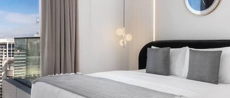 Ett modernt hotellrum med en stor säng, utsikt över staden och en rund väggklocka.