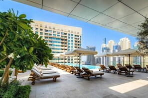A rooftop pool area with lounge chairs and umbrellas, overlooking a cityscape with high-rise buildings. - Exclusive Offer · VIDA Marina 2BR · Luxury (Dubai)