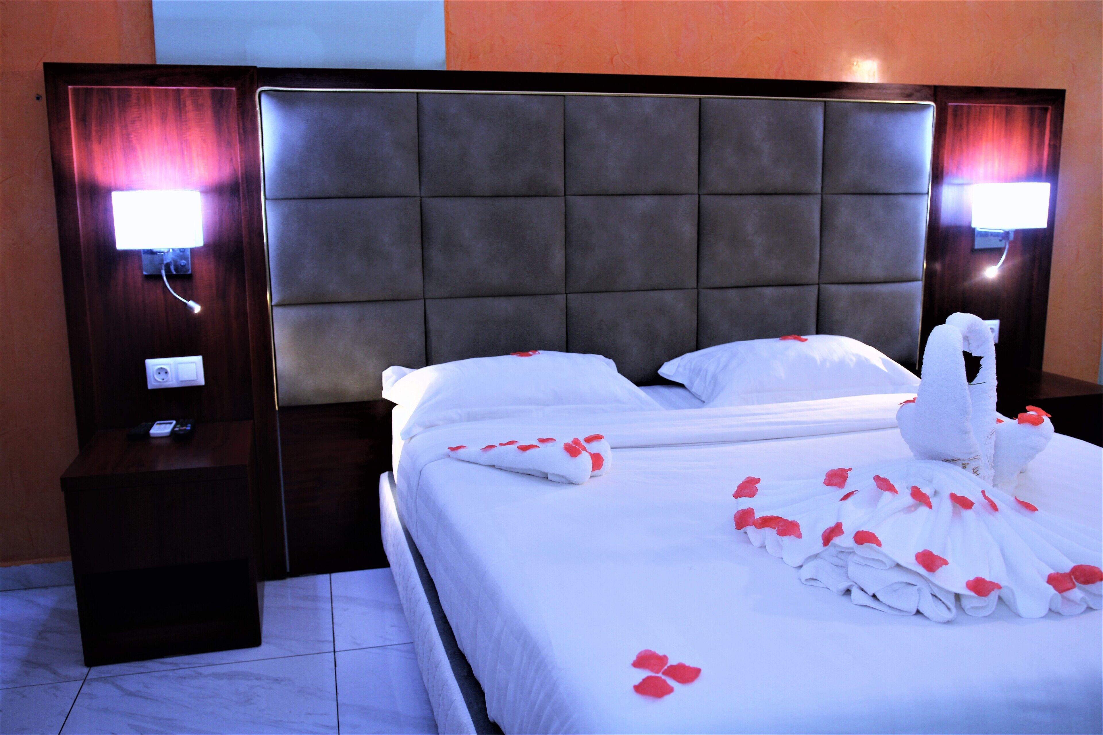 Quarto de hotel com uma cama grande, duas mesas de cabeceira e uma cabeceira.