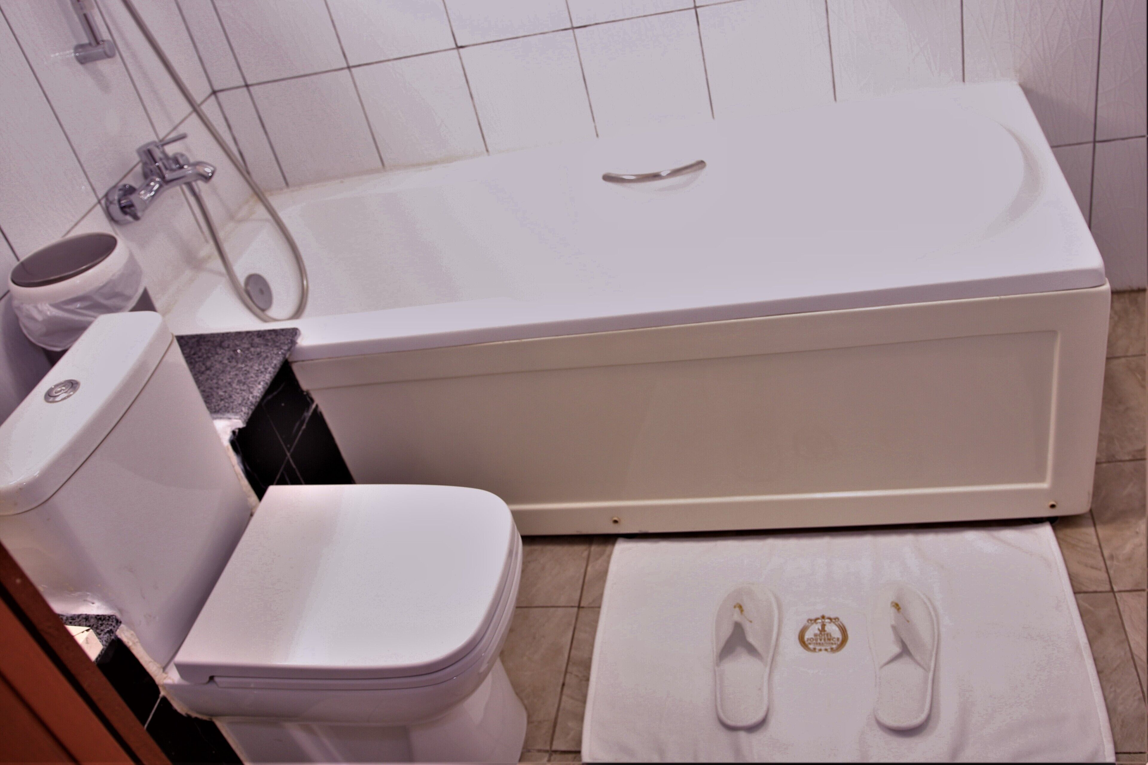 Un baño con bañera, inodoro y una toalla con pantuflas.