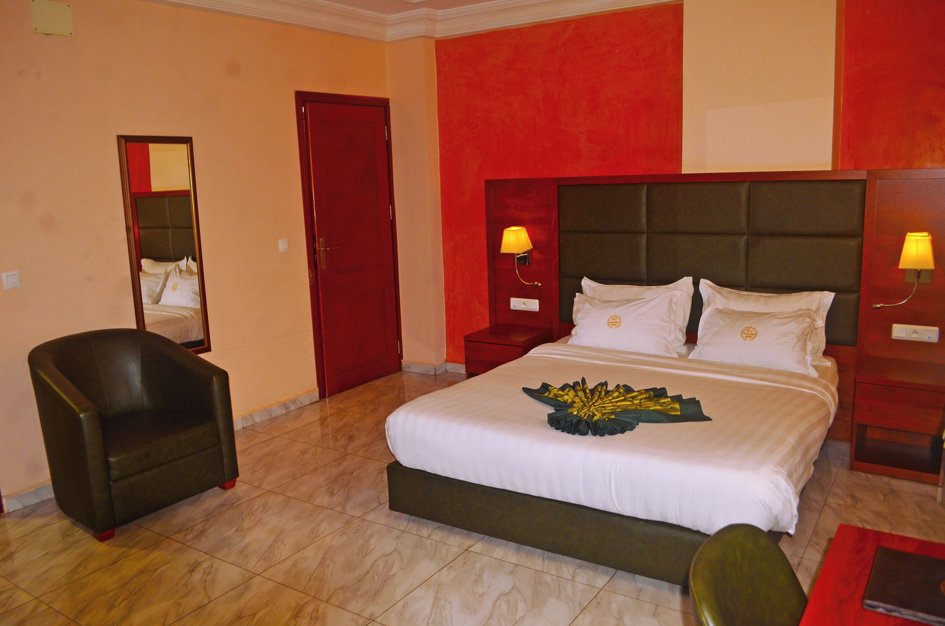 Ein Hotelzimmer mit einem großen Bett, einem Sessel, einem Nachttisch und einem Spiegel.