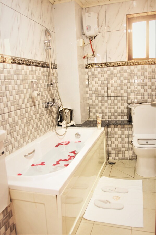 A bathroom with a bathtub, shower, and toilet. - Jouvence International Hôtel (Yaoundé)