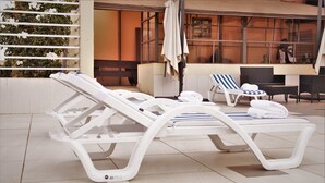 A poolside area with lounge chairs, a table, and a chair. - Jouvence International Hôtel (Yaoundé)