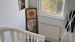 A staircase with white balusters, a radiator, and a window with a view of trees. - Apartmentsleeps2-seaside Escape-wifi-parking (Hastings)