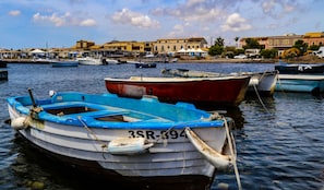 Un port de plaisance avec plusieurs bateaux amarrés, un ciel dégagé et des bùtiments en arriÚre-plan.