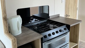 Una cocina compacta con estufa a gas, horno y cafetera.