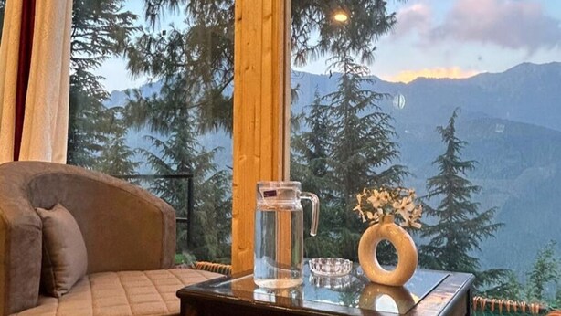 A cozy room with a wooden table, a glass pitcher, and a vase with flowers.
