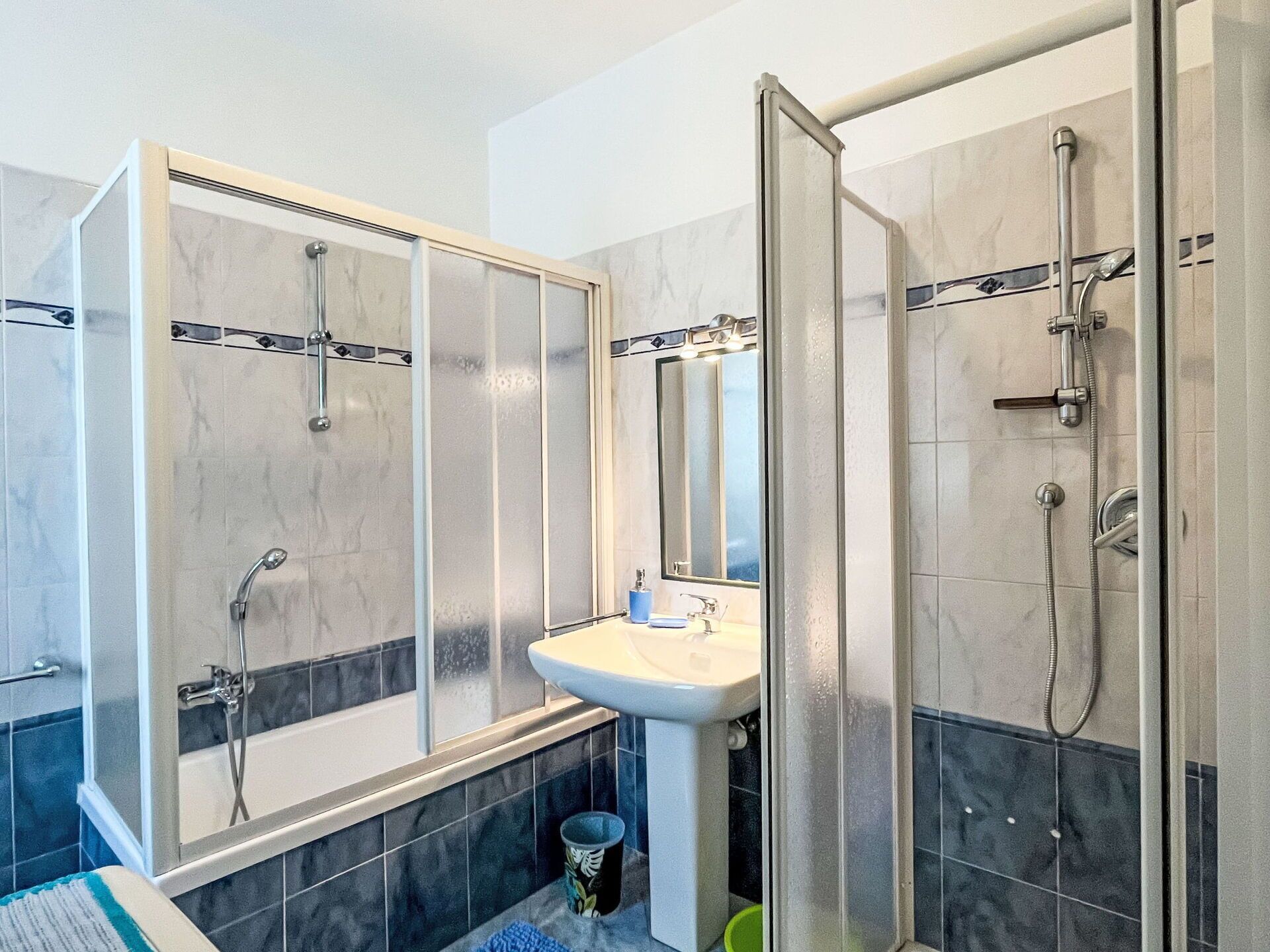 Une salle de bain moderne avec une douche à parois de verre, un lavabo sur colonne et un grand miroir.