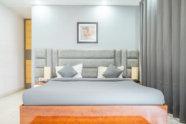 A modern bedroom with a large bed, a headboard, bedside lamps, and a framed picture on the wall.
