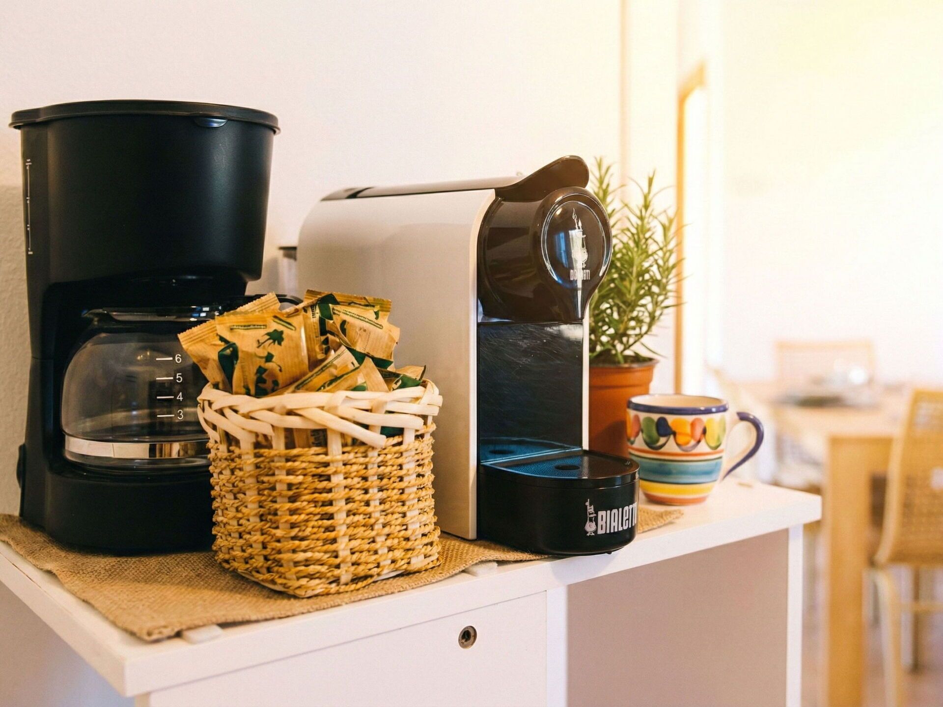 A coffee maker, a basket of coffee pods, and a mug on a countertop.