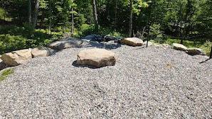 A gravel area with large rocks and trees in the background.