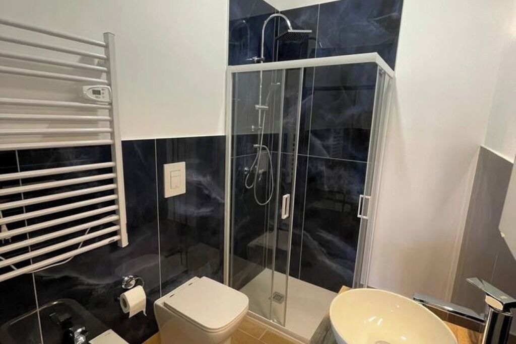 A modern bathroom with a glass-enclosed shower, a white toilet, and a sink with a mirror.
