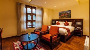 Ein Hotelzimmer mit einem großen Bett, zwei Stühlen, einem kleinen Tisch und einem Bild an der Wand.