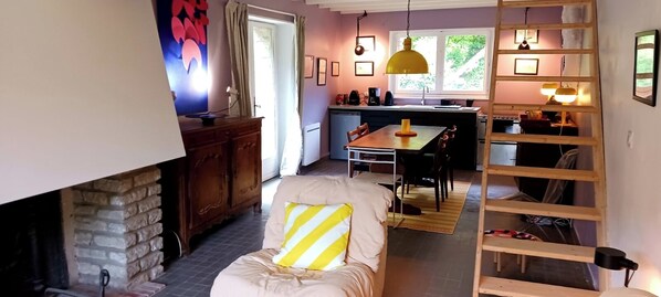 Una sala de estar acogedora con chimenea, comedor y cocina con ventana.