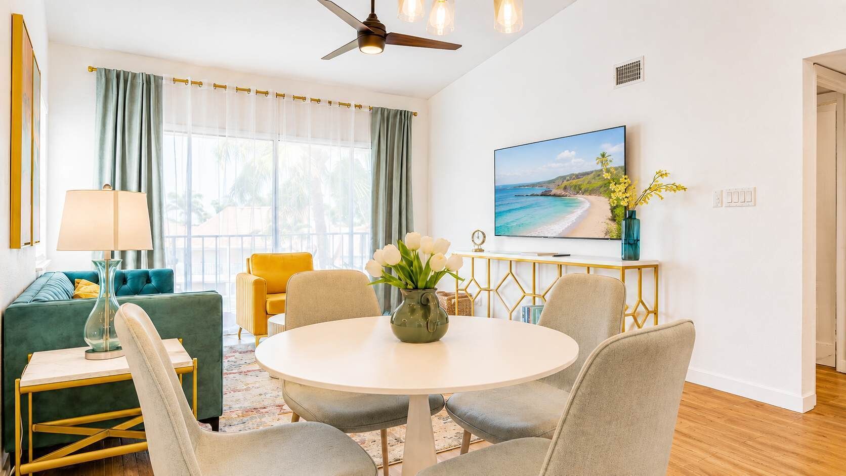 A modern living room with a round dining table, comfortable seating, a television, and a view of the ocean.