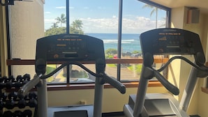Une salle de sport équipée de deux tapis de course, d’un porte-haltères et offrant une vue sur l’océan grâce à de grandes fenêtres.
