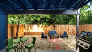 A covered patio with a grill, green chairs, a table, and a blue sofa. - Chic 2BR Escape Sleeps 8  w Private Patio (Austin)