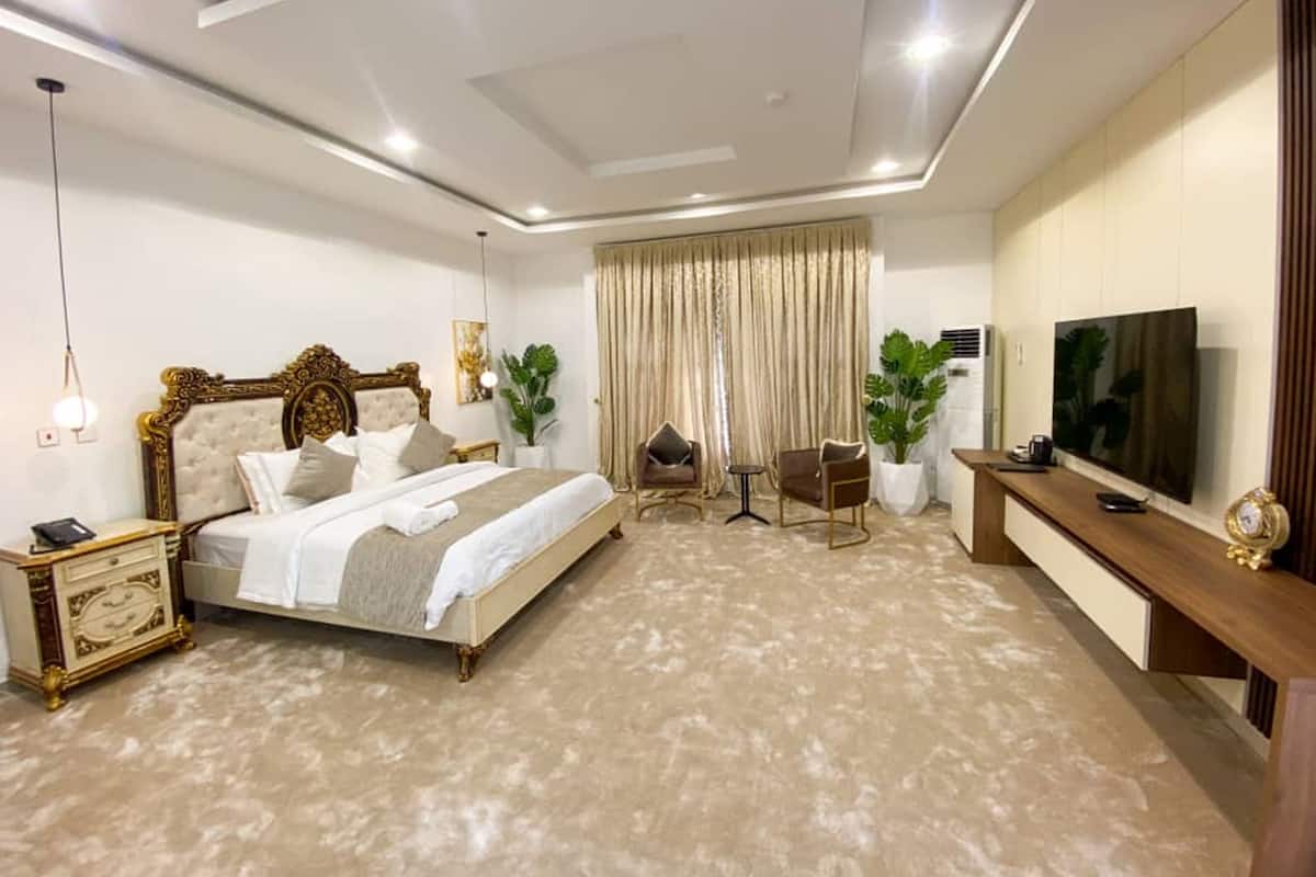 A modern bedroom with a large bed, bedside tables, a TV, and a desk area.