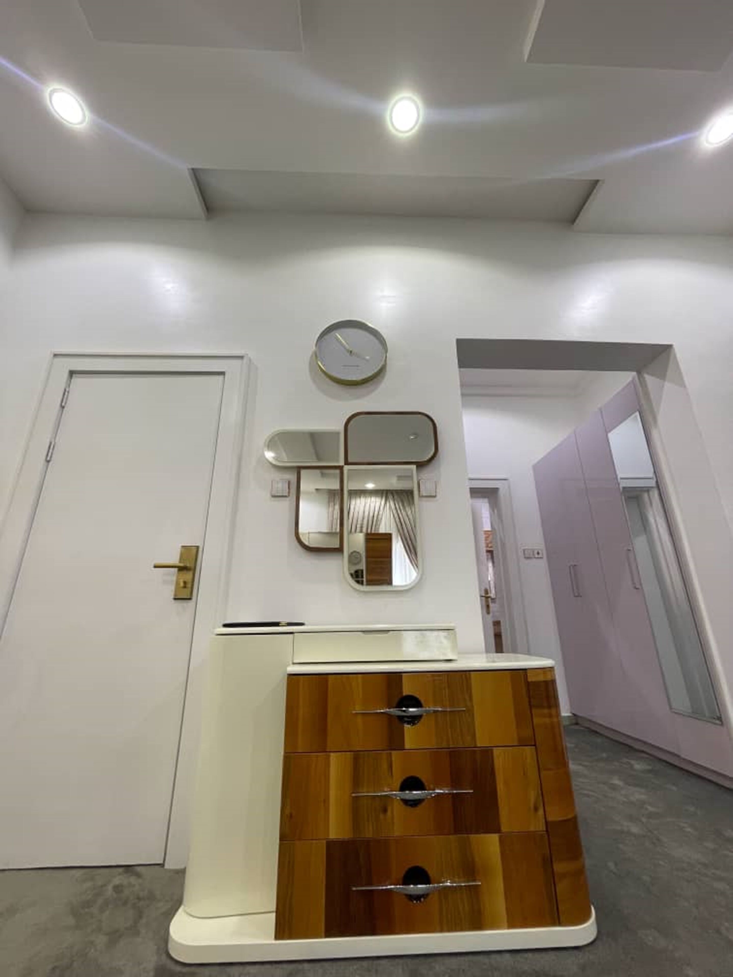 A modern bathroom with a wooden vanity, a wall-mounted mirror, and a ceiling light fixture.