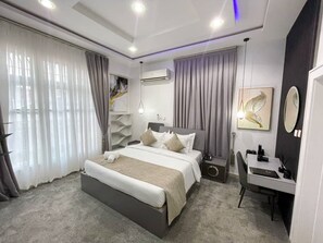 A modern hotel room with a large bed, a desk, and a chair. - UrbanEdge Hotel (Abuja)