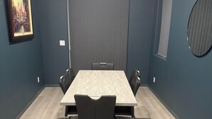 A conference room with a long table, black chairs, and a framed picture on the wall.