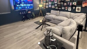 A modern living room with a grey sectional sofa, a flat-screen TV, and a ceiling fan.