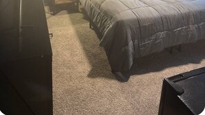 A bedroom with a bed, two bedside lamps, a ceiling fan, and a wall-mounted artwork of a moon.
