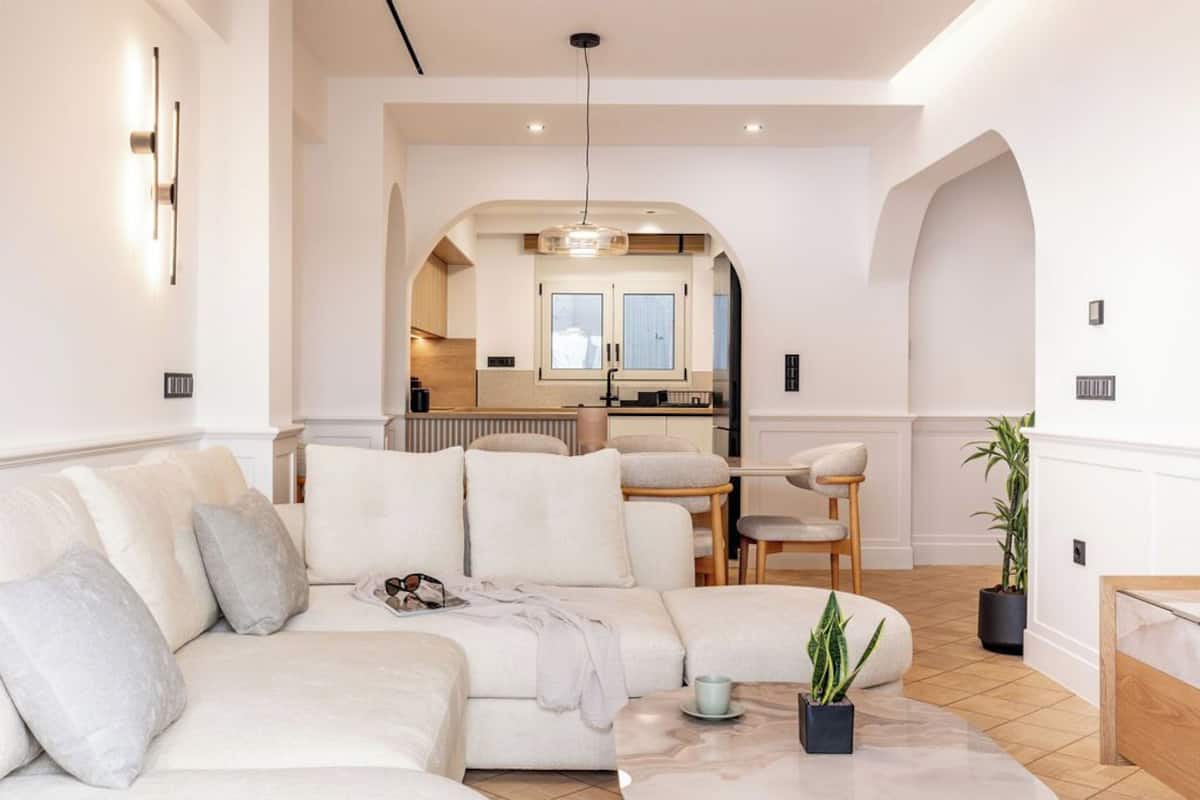 Uma sala de estar moderna com um sofá seccional, uma mesa de centro e vista para a cozinha através de um arco.
