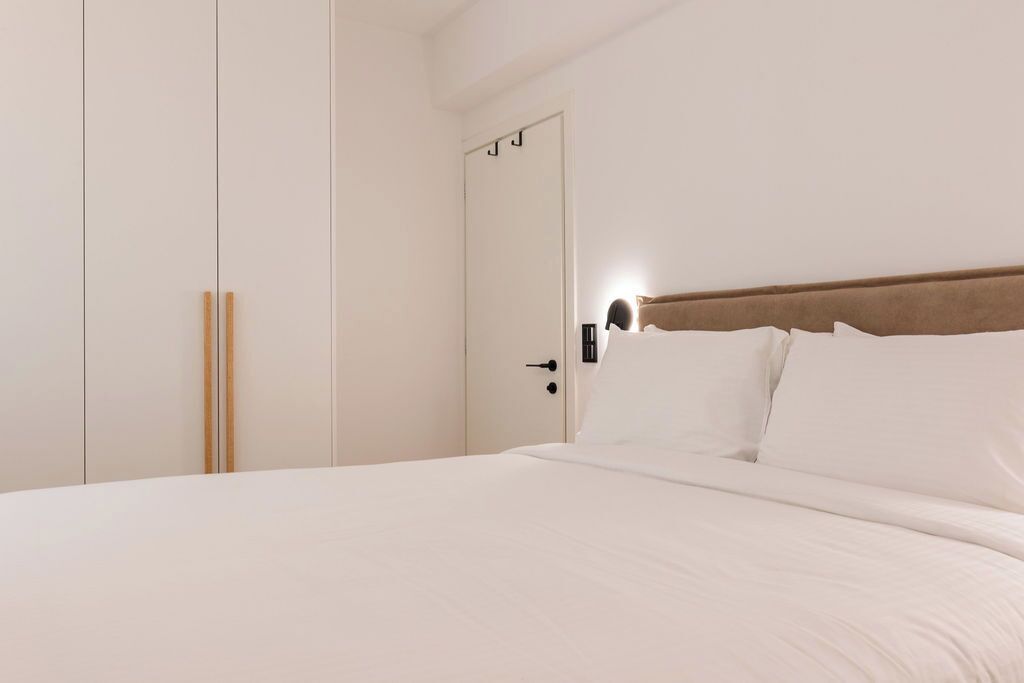 A bedroom with a bed, a wardrobe, and a door.