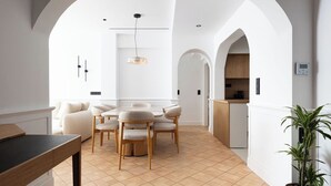 Une cuisine moderne dotée d’un îlot central, de meubles blancs et d’un luminaire suspendu.