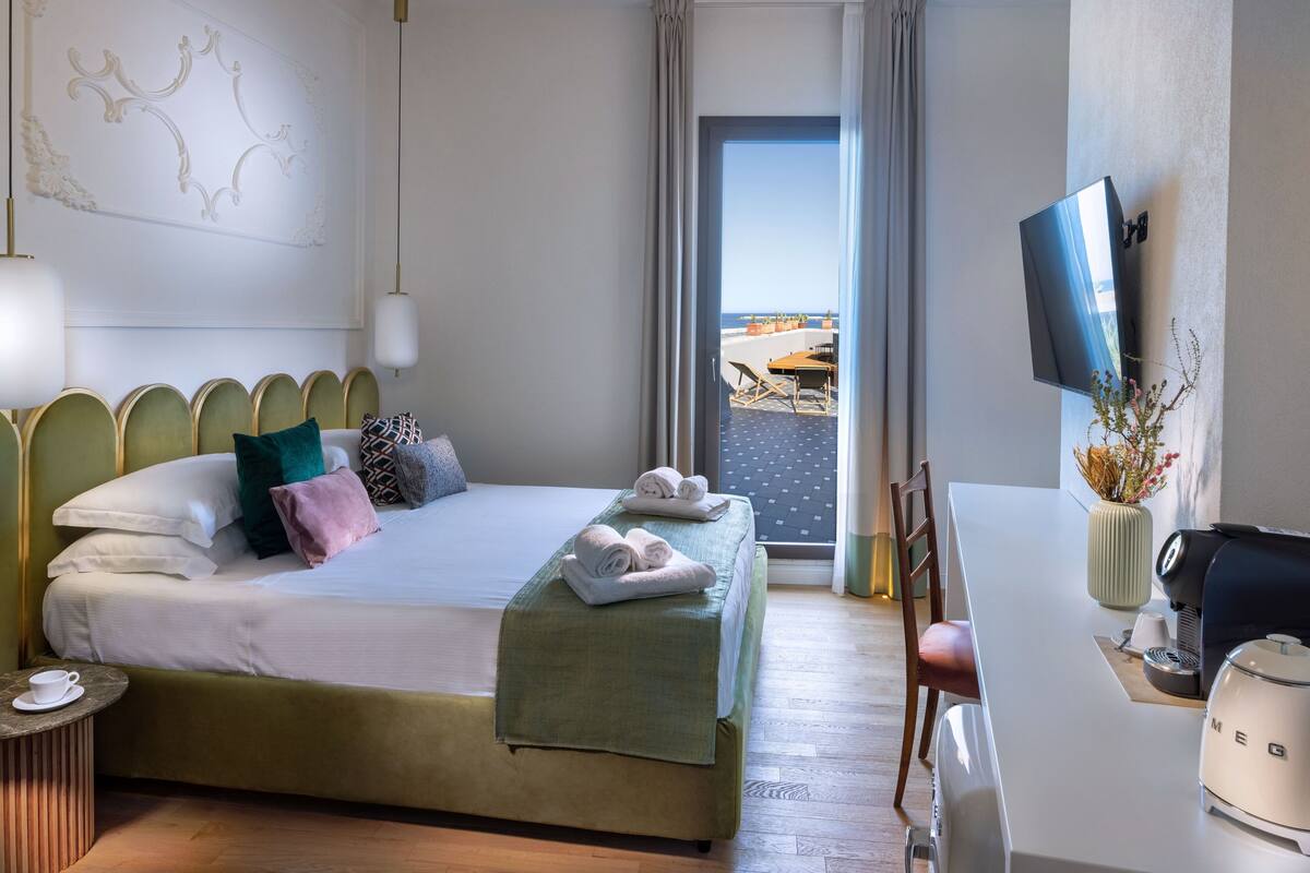 Une chambre d’hôtel avec un lit, un bureau équipé d’une machine à café, une télévision et une vue sur la plage.