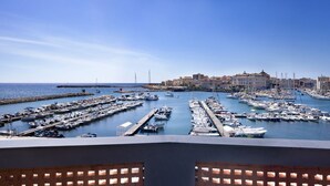 Un port de plaisance où sont amarrés de nombreux bateaux, un ciel bleu dégagé et des bâtiments en arrière-plan.