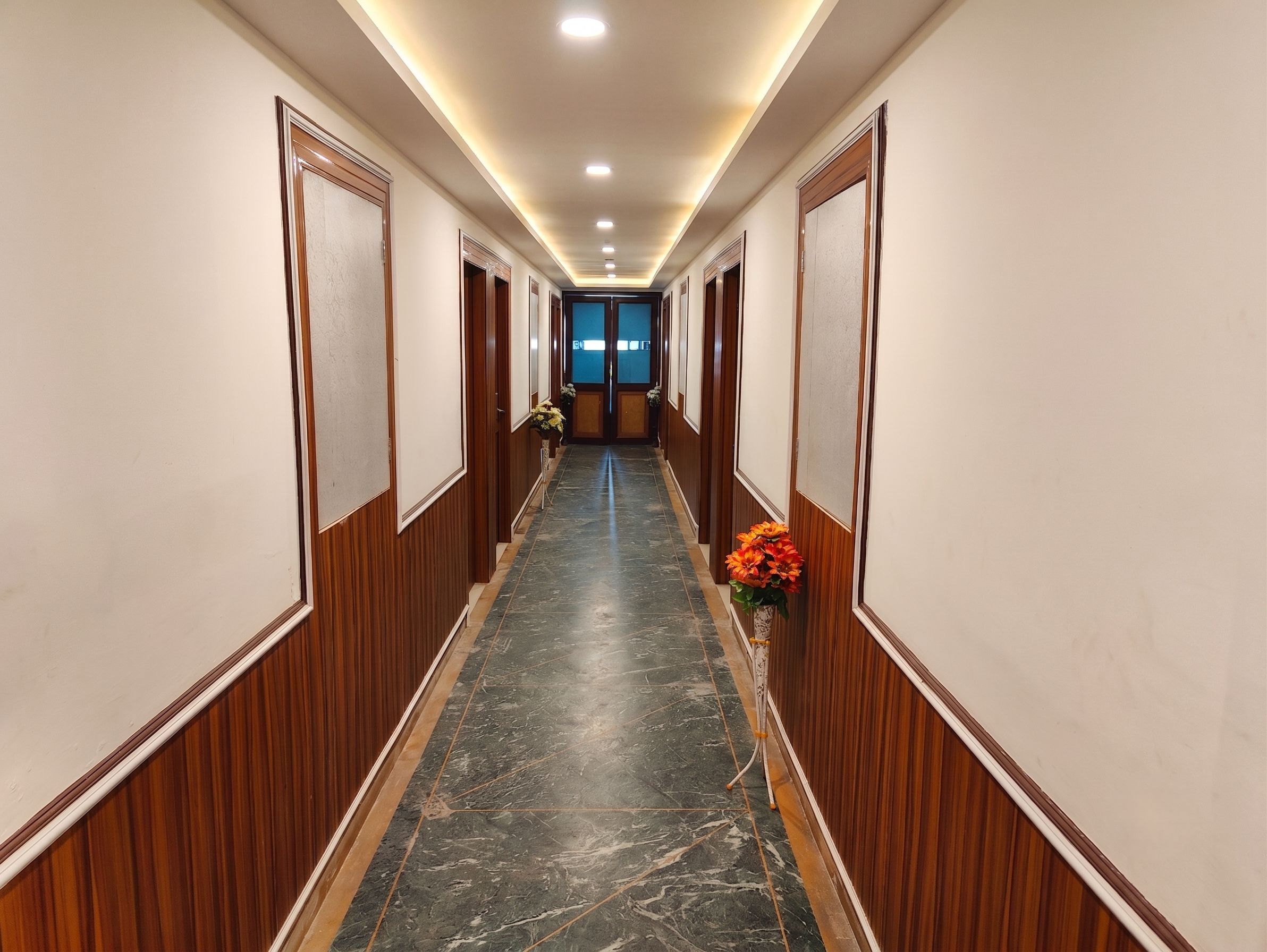 A hallway with wooden paneling, a marble floor, and a door at the end.